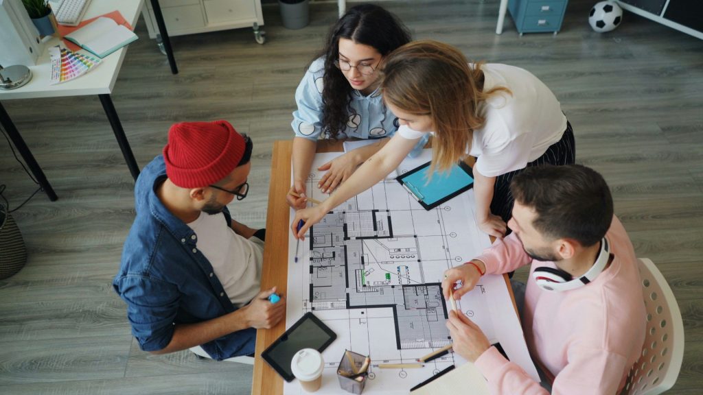 eine Gruppe von Menschen, die um einen Tisch sitzen und an einem Projekt arbeiten
